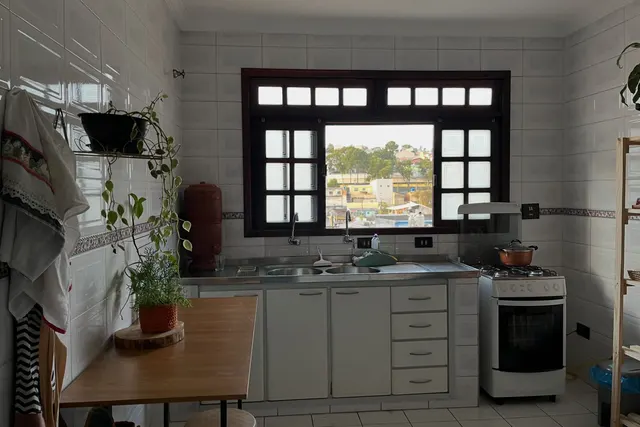 A cozinha antes: azulejo branco, armários claros e bancada de inox