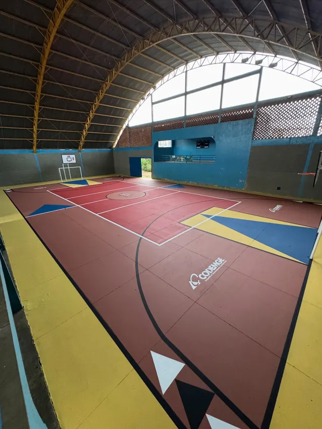 A mesma quadra coberta depois: piso vermelho, amarelo e azul com formas geométricas