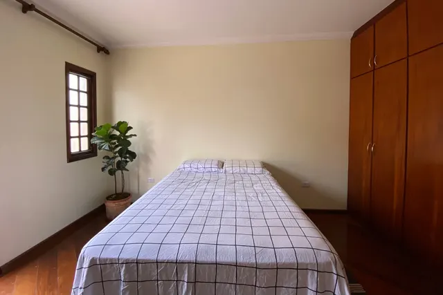 O quarto antes: paredes creme e cama com roupa de cama xadrez