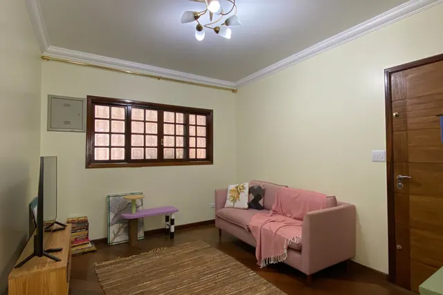 A sala antes: paredes creme, sofá rosa e tapete de sisal