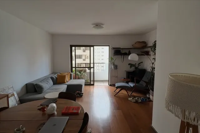 A sala de estar antes: paredes brancas, sofá cinza e piso de madeira